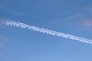 Estelas de condensación de aviones en el cielo azul entre algunas nubes foto