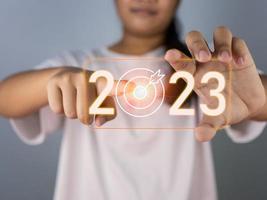 woman pointing at dart board icon Represents the goal setting for 2023, concept of startup, financial planning, development strategy, business goal setting. photo