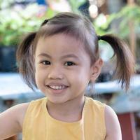 Positive charming 4 years old cute baby Asian girl, little preschooler child with adorable pigtails hair smiling looking to camera. photo