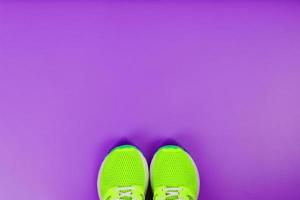 Green running shoes on a purple background. photo