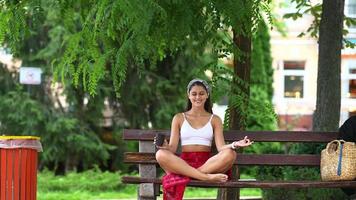 jeune belle femme est assise sur un banc de parc avec une tasse et un téléphone souriant puis ferme les yeux video