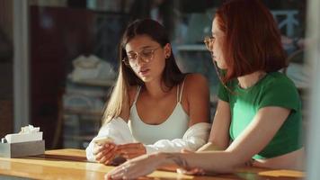 Two women talk and hang out at sunny coffee shop video