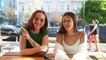 Two women talk and hang out at sunny coffee shop video