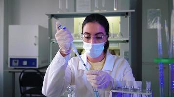 Female Scientist in laboratory doing chemical experiment with blue liquid in test tubes. Extraction DNA and molecules. Vaccine development. Research, biochemistry, pharmaceutical medicine concept. video