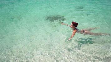 mulher esbelta em um maiô nada em um mar claro em um dia ensolarado. conceito de férias de verão. câmera lenta. video