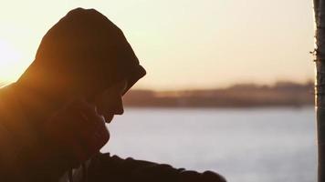 silhouette d'un boxeur sur fond d'un beau coucher de soleil et d'une rivière dans un bâtiment abandonné, s'entraîne à coups sur un sac de boxe. vidéo épique. motivation. sports et arts martiaux. ralenti. video