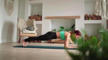 mujer atlética en ropa deportiva haciendo ejercicio en casa, haciendo una tabla de ejercicios. chica en forma deportiva dedicada a ejercicios aeróbicos de fitness en el dormitorio. salud corporal. concepto de entrenamiento, entrenamiento y bienestar en el hogar. video