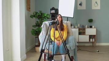 mooi meisje blogger filmen haar video blog. vrouw influencer creëert online opleiding Cursus voor afgelegen werk. aantrekkelijk vrouw in geel trui bloggen. afstand onderwijs en e-learning concept.