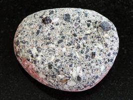 pebble of gray Arkose sandstone on dark background photo