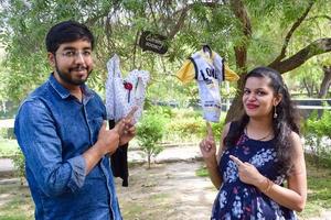 Indian couple posing for maternity baby shoot. The couple is posing in a lawn with green grass and the woman is falunting her baby bump in Lodhi Garden in New Delhi, India photo