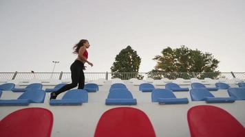 Young athletic girl is jogging. Runs along the stands. Slow motion. Overall plan. video