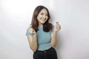una atractiva joven asiática con una camiseta azul se siente feliz y un gesto romántico del corazón expresa sentimientos tiernos foto