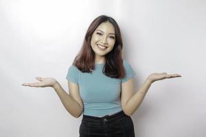 Excited Asian woman wearing blue t-shirt pointing at the copy space beside her, isolated by white background photo