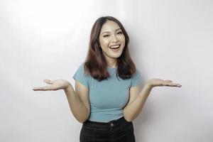 Excited Asian woman wearing blue t-shirt pointing at the copy space beside her, isolated by white background photo