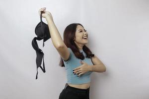 Woman smiling and holding a bra against white background. Concept of Breast cancer awareness and international no bra day celebration photo