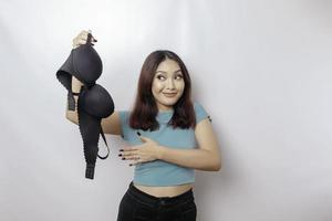 Woman smiling and holding a bra against white background. Concept of Breast cancer awareness and international no bra day celebration photo