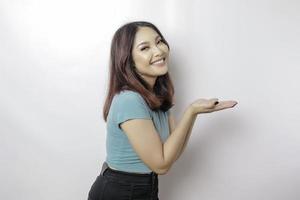 Excited Asian woman wearing blue t-shirt pointing at the copy space beside her, isolated by white background photo