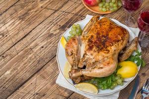 Baked chicken, wine glasses and fruit for dinner on the festive table. copy space photo