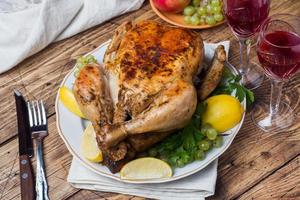 Baked chicken, wine glasses and fruit for dinner on the festive table. photo