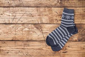 Gray winter socks in stripes with snowflakes with copy space. Socks on wooden background. photo