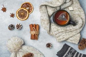 Winter vacation concept. Warm clothes, Cup of hot tea with fragrant spices on grey background. photo