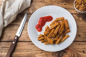 Croutons of grain bread with spices in the dishes. Wooden background. photo