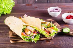 Tortilla wraps with chicken, cucumber and tomato on a board on the table. Mexican cuisine photo