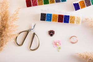 Containers with colored beads, wire and scissors for making toys from beads. Needlework and handmade photo