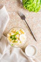 Potato salad with boiled egg, green onion and mayonnaise in a bowl. Top and vertical view photo