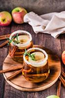 Homemade organic apple cider with cinnamon and rosemary in glasses on the table. Vertical view photo