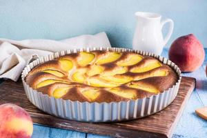 Sweet peach pie in a baking dish on the table. Homemade dessert photo