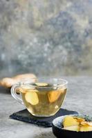 Fresh ginger tea in a cup and chopped ginger in a bowl on the table. Natural Vitamins. Vertical view photo