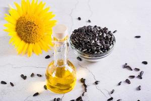 Sunflower seeds, oil in a bottle and a flower on the table. Organic products. photo