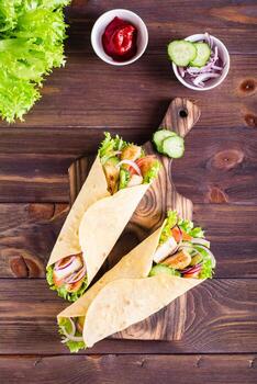 envolturas de tortilla con pollo, pepino y tomate en un tablero. cocina mexicana. vista superior y vertical foto