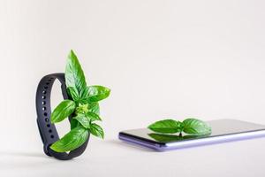 Fresh leaves on the screen of a fitness bracelet and on a smartphone. The concept of health care photo