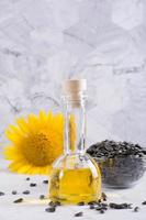 Sunflower oil in a bottle and seeds in a bowl on the table. Harvest and natural nutrition. Vertical photo