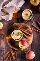 Homemade organic apple cider with cinnamon and rosemary in glasses on the table. Top and vertical photo