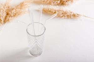 Glass reusable straws for drinks and cleaning brush in a glass on the table. Sustainable lifestyle. photo