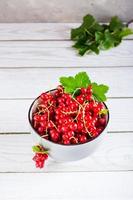Fresh red currant berries in a bowl on the table. Summer organic food. Vertical view photo