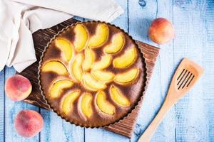 Ready fresh peach pie in a baking dish on the table. Homemade dessert. Top view photo