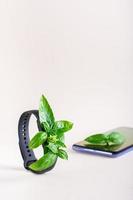 Fresh leaves on the screen of a fitness bracelet and on a smartphone. The concept of health care. Vertical view photo