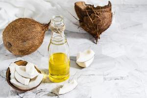 Fresh vegetable coconut oil in a bottle and pieces of coconut on the table. Copy space photo