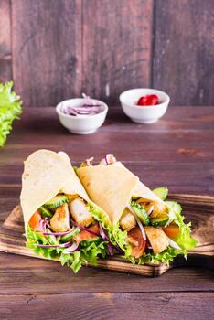 envolturas de tortilla con pollo, pepino y tomate en un tablero. cocina mexicana. vista vertical foto