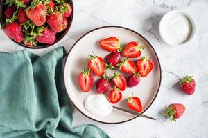 Fresh sliced strawberries and yogurt on a plate on the table. Healthy vitamin dessert. Top view photo