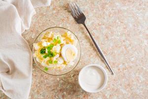 Homemade potato salad with egg and green onions in a bowl on the table. Top view photo