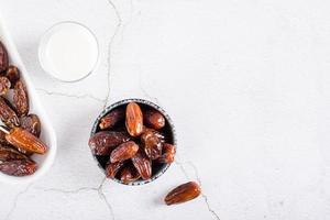 Dates in a bowl and a glass of milk on the table. Food for the holy month of Ramadan. Top view photo