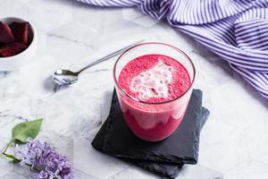Sweet beetroot latte with milk foam in a glass on the table. Healthy homemade vitamin drinks