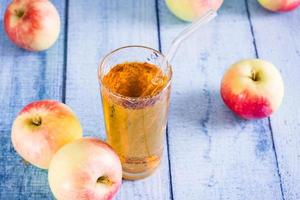 Organic homemade apple juice in a glass with a straw and fruits on the table photo