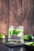 Refreshing water with cucumber in a glass on the table. Homemade antioxidant drinks. Vertical view photo