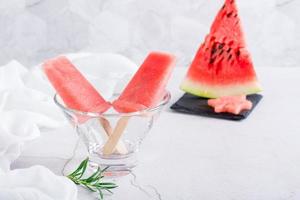 Watermelon popsicles in a bowl and a piece of watermelon on the table. Homemade dessert photo